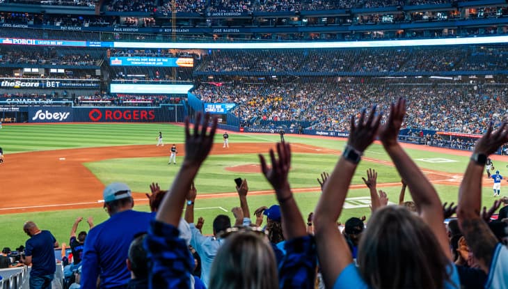 A crowd with their hands up at a Blue Jays game in the Rogers Centre