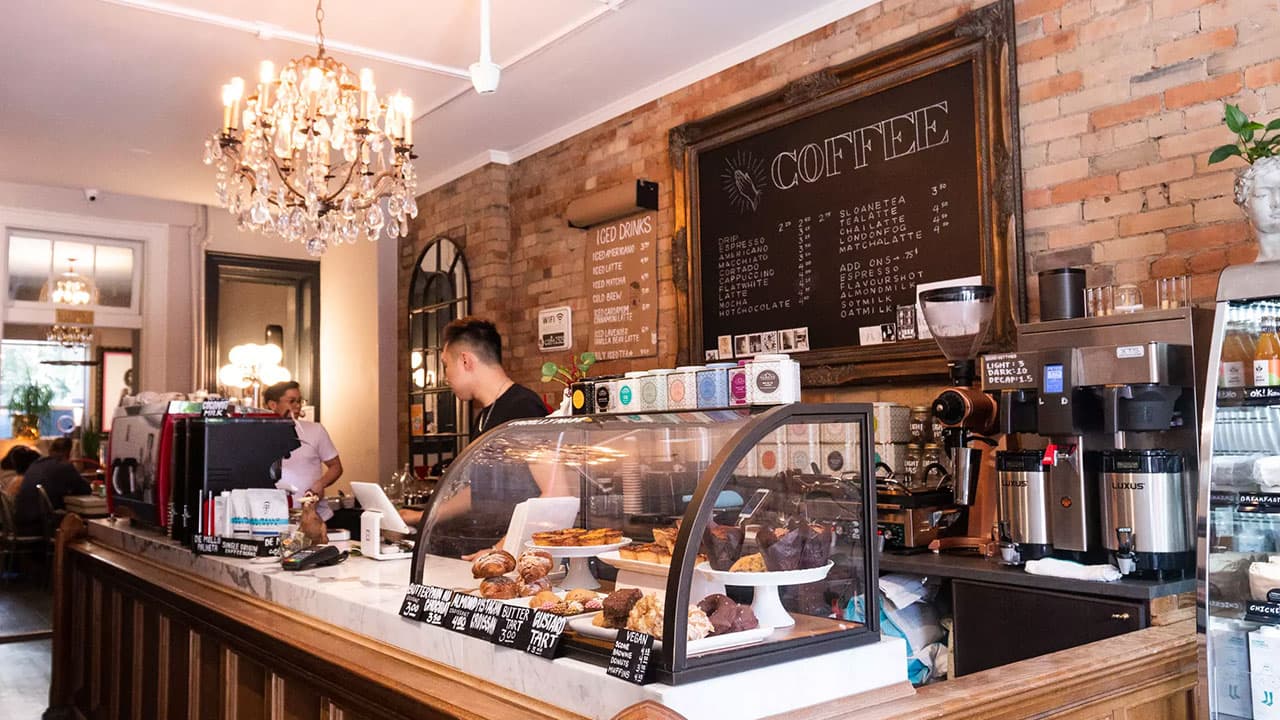 A café counter with a pastry case and a chalkboard coffee menu